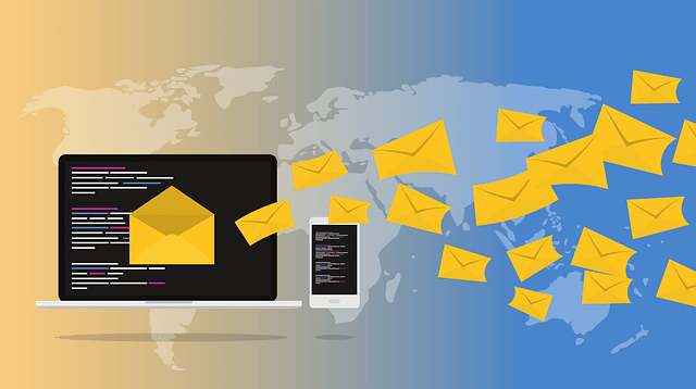 A laptop and smartphone displaying code with yellow email icons flying toward a world map.